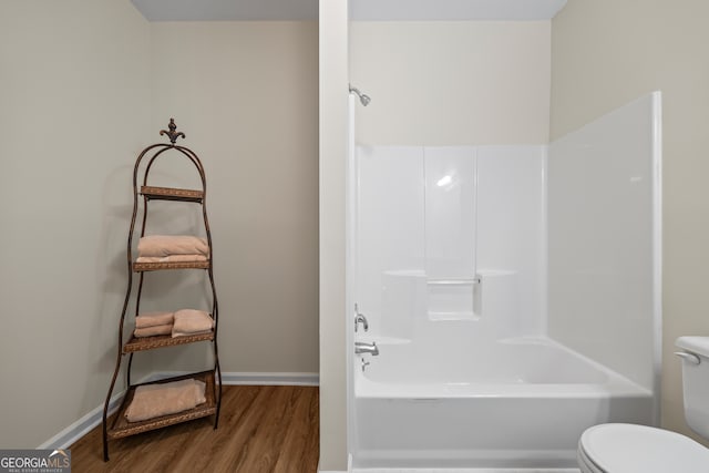 full bathroom featuring wood finished floors, toilet, baseboards, and bathtub / shower combination
