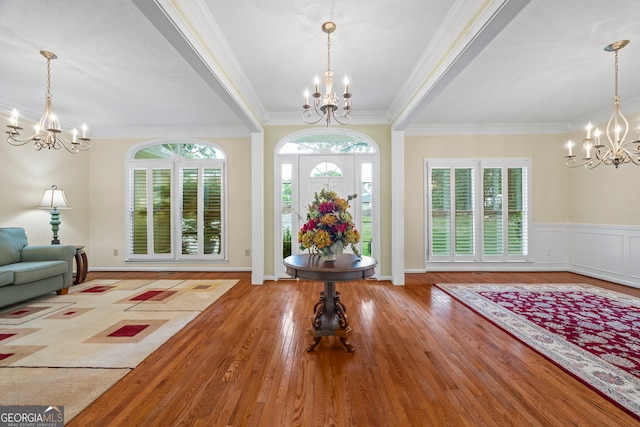 foyer entrance with a chandelier, crown molding, and wood finished floors