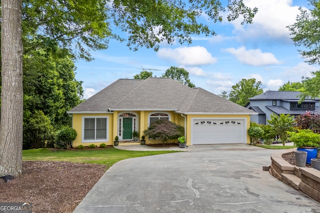 view of front of property with concrete driveway, a shingled roof, an attached garage, and a front yard