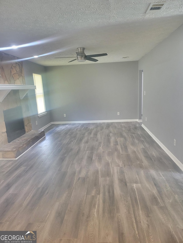 324 Cynthia Ct, Jonesboro, GA 30238 - unfurnished living room featuring a ceiling fan, a textured ceiling, a stone fireplace, wood finished floors, and baseboards