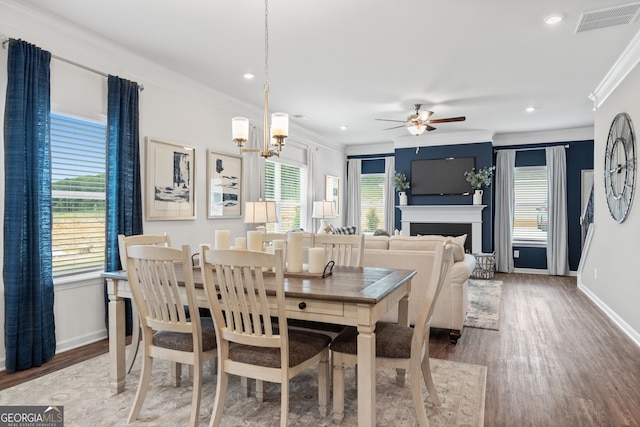 dining area featuring ornamental molding, wood finished floors, baseboards, ceiling fan, and a fireplace
