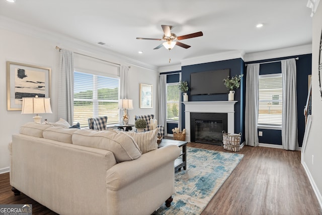 living room featuring a ceiling fan, ornamental molding, baseboards, dark wood finished floors, and recessed lighting