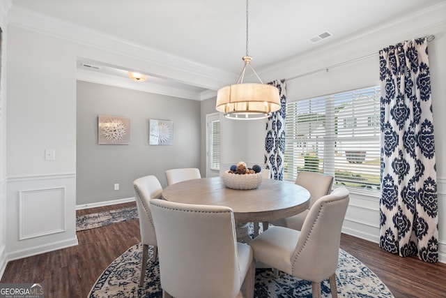 dining area featuring crown molding, dark wood finished floors, and a wainscoted wall