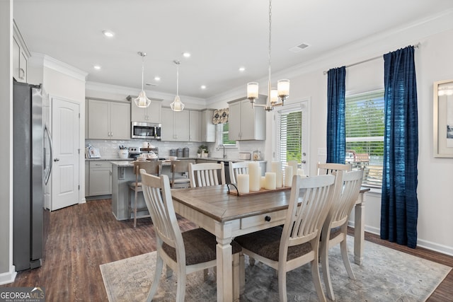 dining room featuring dark wood-type flooring, ornamental molding, a chandelier, and recessed lighting