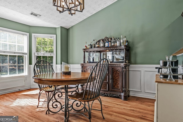 108 Wortham Dr, Buckhead, GA 30625 - dining area featuring light wood-type flooring, a textured ceiling, wainscoting, a chandelier, and a dry bar