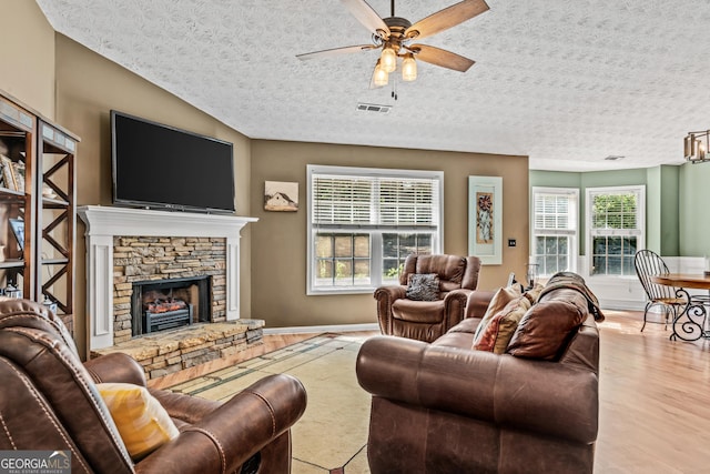 108 Wortham Dr, Buckhead, GA 30625 - living area with a ceiling fan, plenty of natural light, a stone fireplace, wood finished floors, and a textured ceiling
