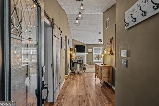 108 Wortham Dr, Buckhead, GA 30625 - corridor with a barn door, wood finished floors, a textured ceiling, baseboards, and lofted ceiling