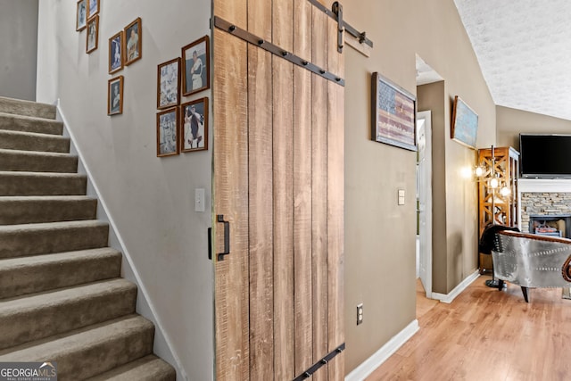 108 Wortham Dr, Buckhead, GA 30625 - stairway featuring wood finished floors, a barn door, a textured ceiling, baseboards, and a fireplace