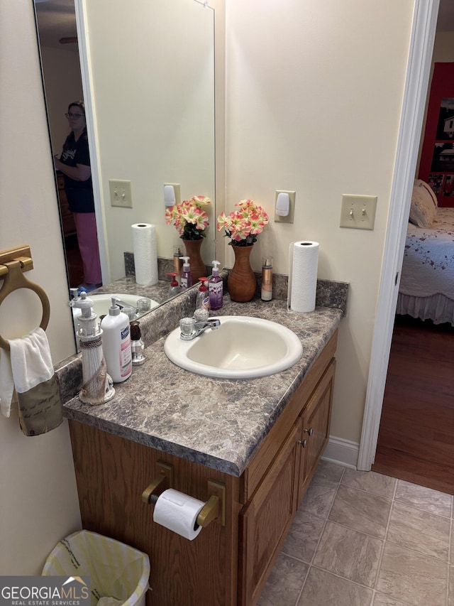 bathroom with connected bathroom, vanity, and baseboards