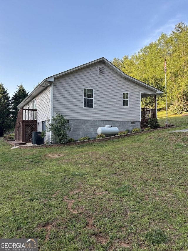 view of side of property with a lawn, central AC unit, and crawl space