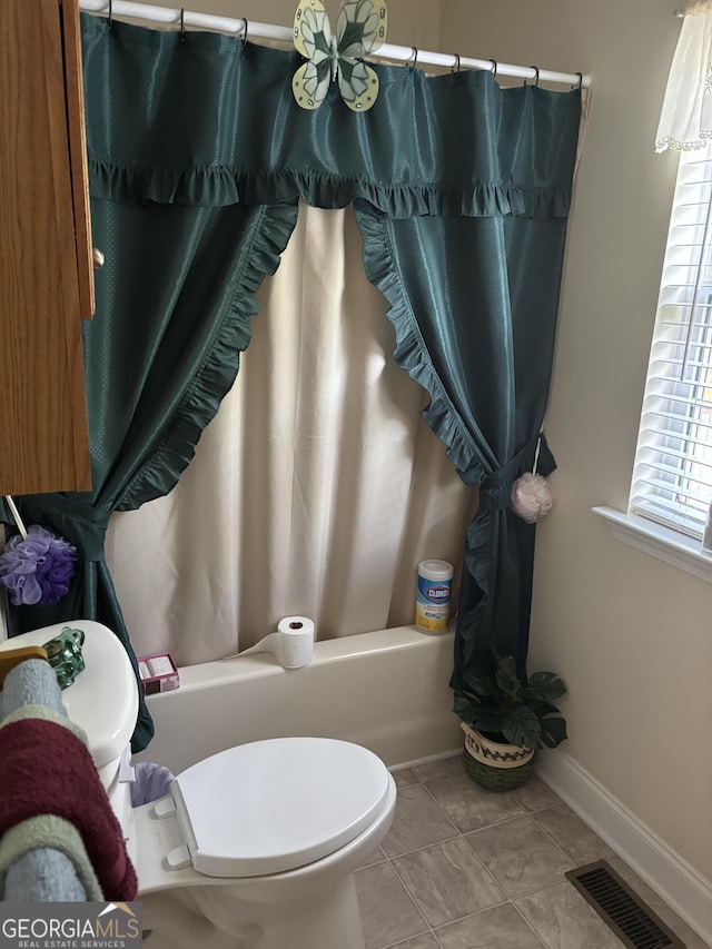 bathroom featuring toilet, baseboards, and shower / tub combo