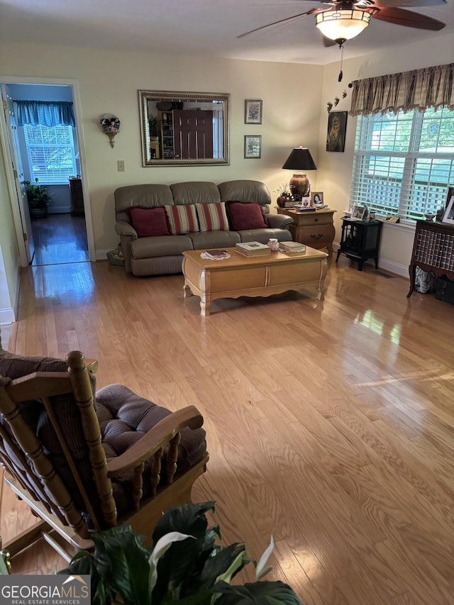 living area featuring ceiling fan, light wood-type flooring, and baseboards