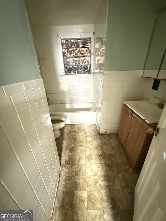 full bath with tile walls, toilet, vanity, wainscoting, and a shower