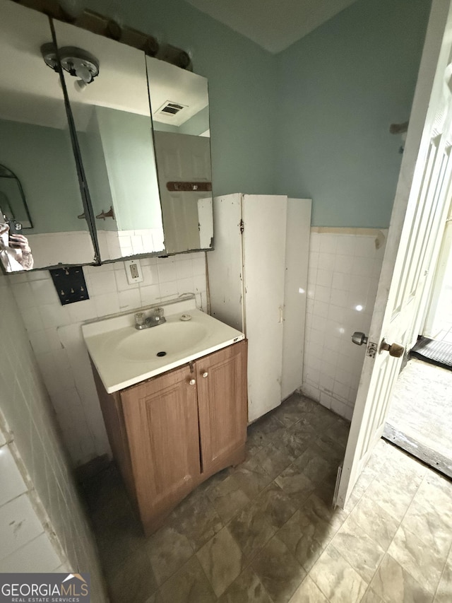 bathroom featuring tile walls, wainscoting, and vanity