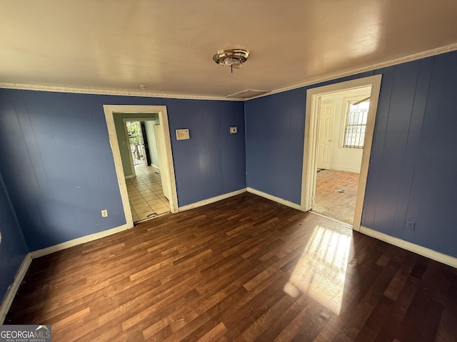 unfurnished room featuring wood finished floors, plenty of natural light, baseboards, and crown molding