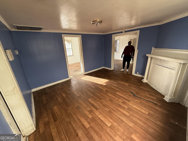 spare room with healthy amount of natural light, wood finished floors, baseboards, and ornamental molding