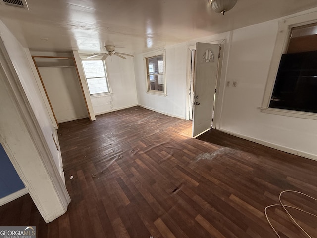 empty room with dark wood-style flooring, ceiling fan, and baseboards