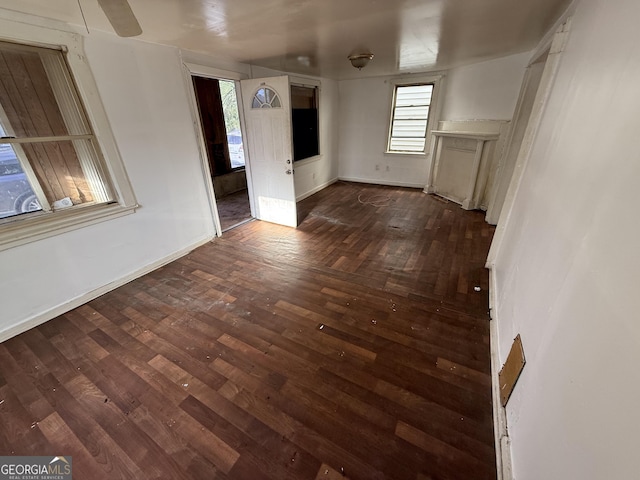 unfurnished living room with baseboards and dark wood-style floors