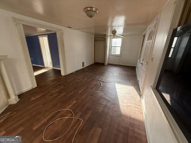 empty room featuring a ceiling fan, dark wood finished floors, and baseboards