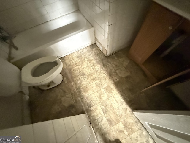 full bathroom with toilet, a bathtub, and tile walls