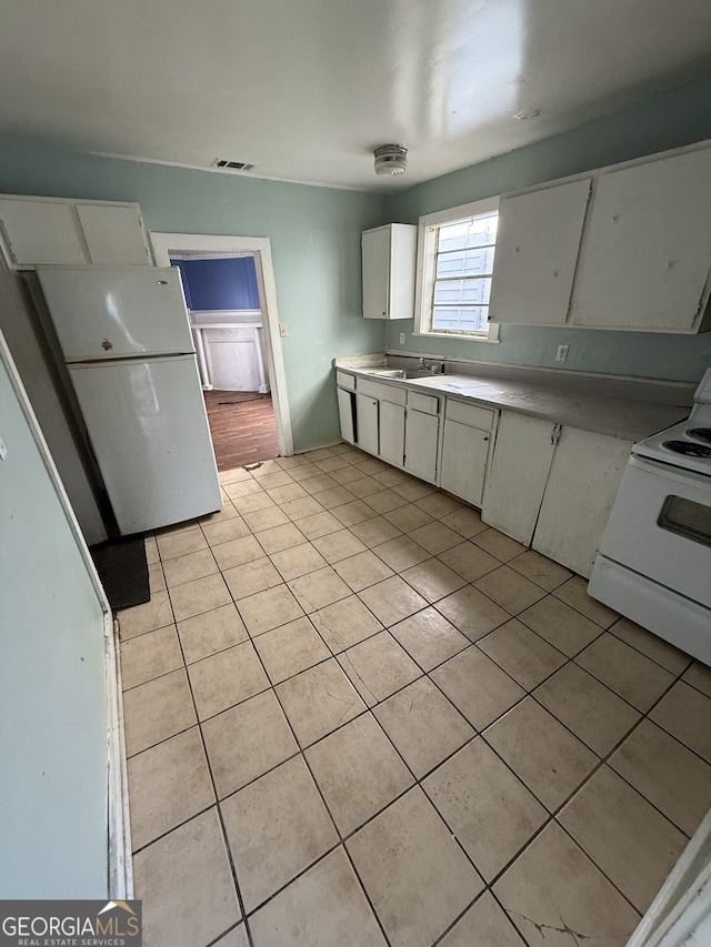 kitchen with white appliances, light tile patterned floors, light countertops, a sink, and white cabinetry