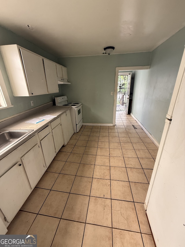 kitchen with white electric stove, light tile patterned floors, under cabinet range hood, and white cabinets