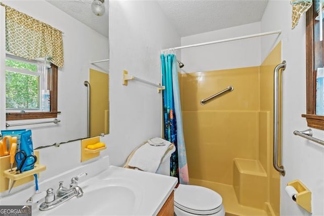 bathroom with a textured ceiling, curtained shower, vanity, and toilet