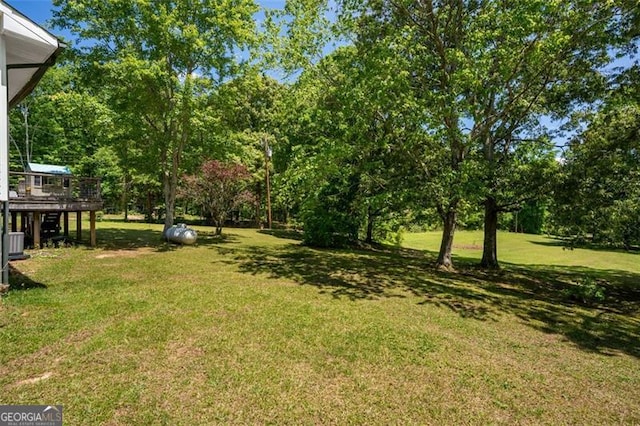 view of green lawn featuring a deck and view of wooded area