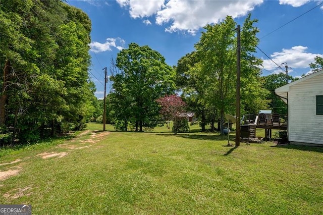 view of grassy yard featuring a wooden deck