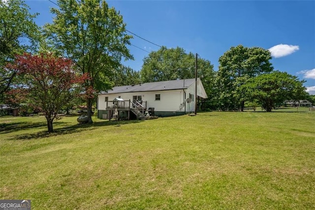 view of green lawn featuring stairs and a deck