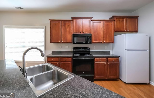 416 Clarion Dr, Carrollton, GA 30116 - kitchen featuring black appliances, a sink, dark countertops, light wood-style flooring, and brown cabinetry