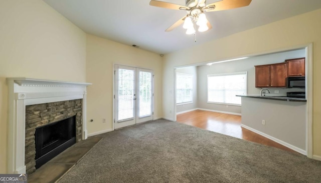 416 Clarion Dr, Carrollton, GA 30116 - unfurnished living room with dark colored carpet, a stone fireplace, a ceiling fan, and baseboards