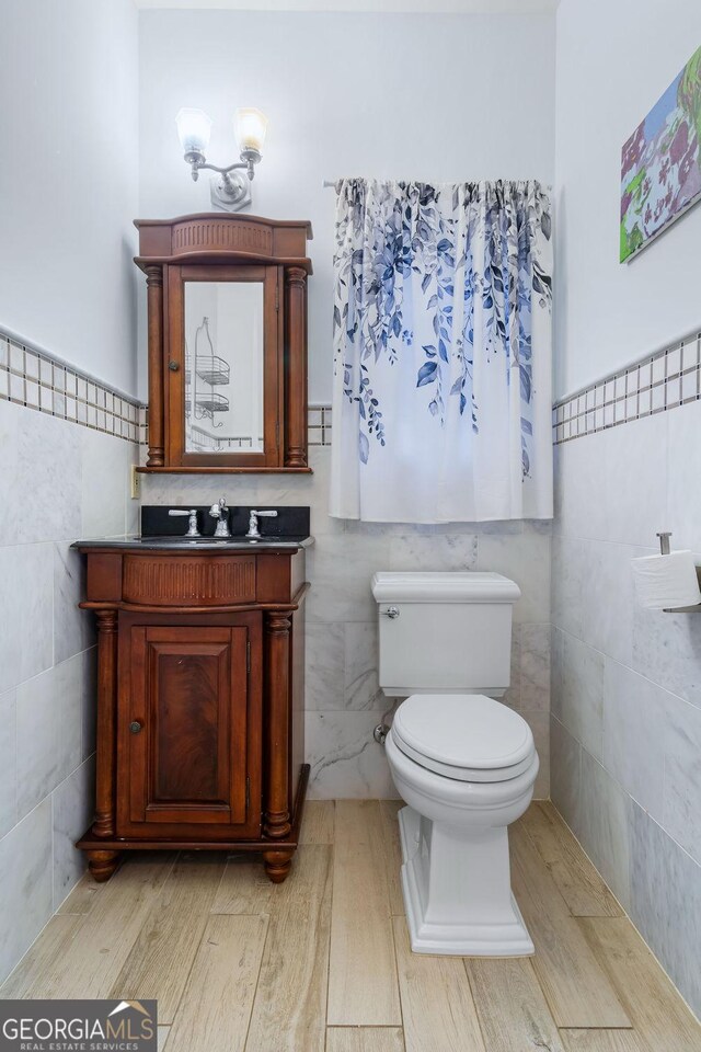 114 N Valhalla Dr, Cordele, GA 31015 - bathroom featuring tile walls, toilet, vanity, wood finished floors, and wainscoting