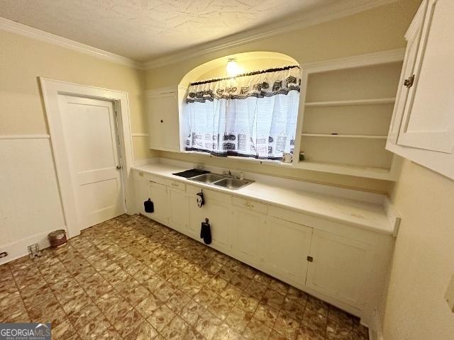 210 W Church St, Swainsboro, GA 30401 - kitchen featuring white cabinets, a sink, light countertops, crown molding, and tile patterned floors