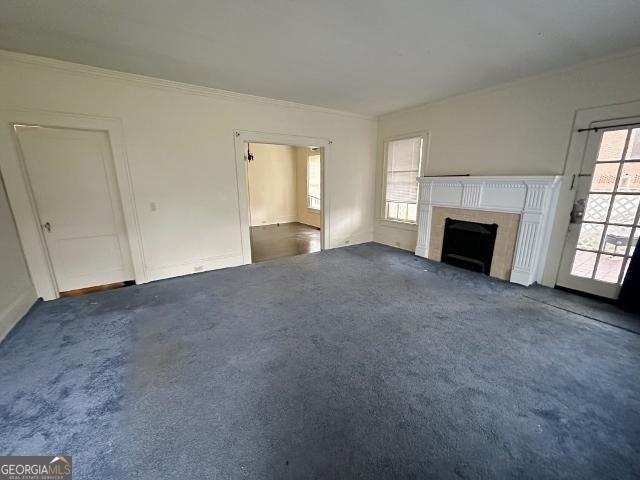 210 W Church St, Swainsboro, GA 30401 - unfurnished living room featuring carpet floors, crown molding, a fireplace, and baseboards