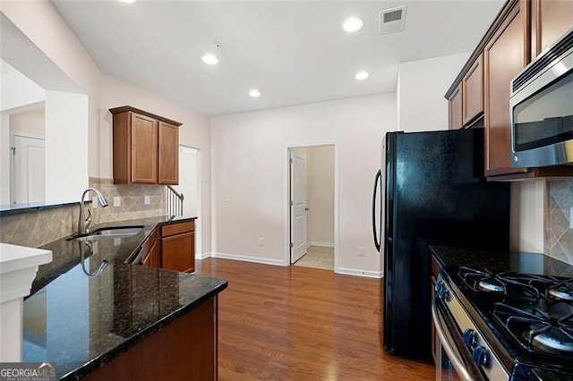 1957 Brightleaf Way Unit 59, Marietta, GA 30060 - kitchen featuring stainless steel appliances, a sink, dark stone countertops, decorative backsplash, and dark wood-type flooring