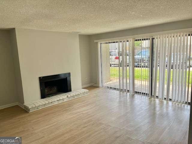 3575 Oakvale Rd Unit 1103, Decatur, GA 30034 - unfurnished living room featuring wood finished floors, a fireplace, baseboards, and a textured ceiling