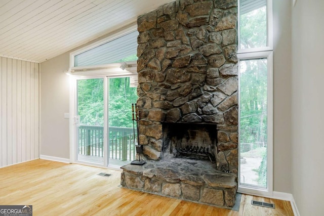 unfurnished living room with wood finished floors, baseboards, lofted ceiling, a stone fireplace, and wooden ceiling