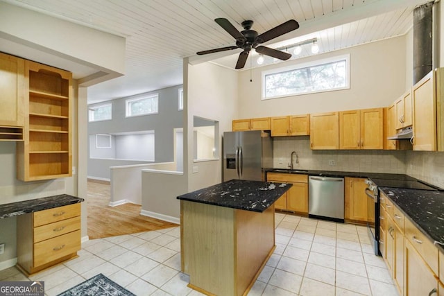 kitchen featuring appliances with stainless steel finishes, light tile patterned floors, backsplash, a center island, and ceiling fan