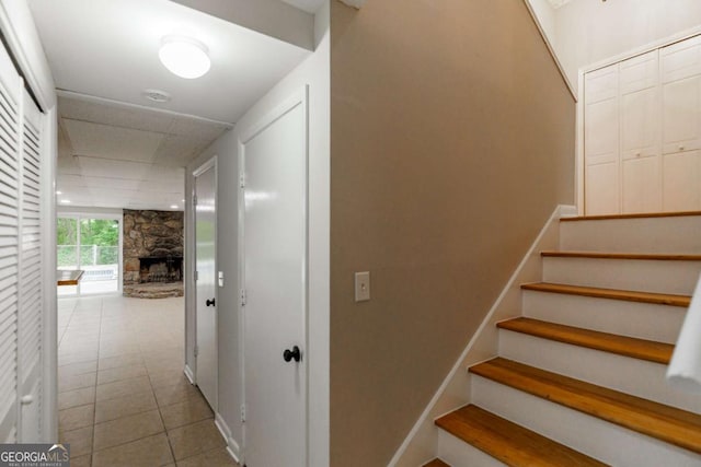 stairway with tile patterned floors, a fireplace, and a drop ceiling