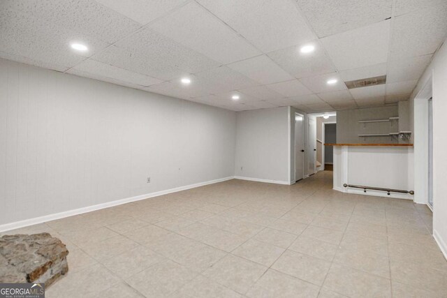 unfurnished living room with recessed lighting, baseboards, and a drop ceiling