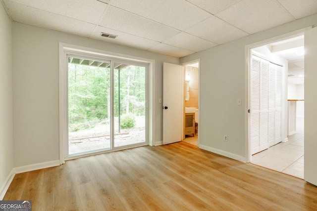 empty room featuring baseboards, a paneled ceiling, and wood finished floors