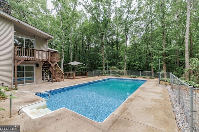 view of pool with stairs, a wooden deck, fence, and a patio area
