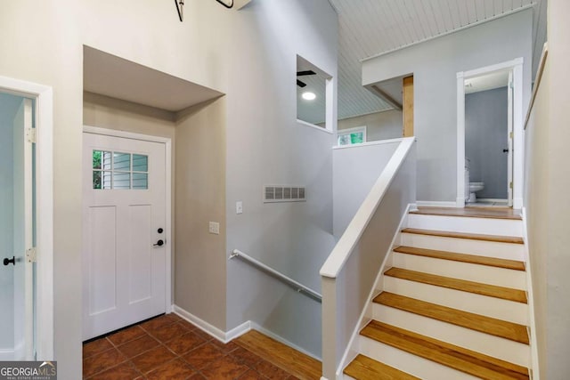 foyer with plenty of natural light, baseboards, stairway, and dark tile patterned floors