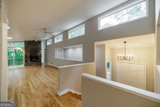 corridor with wood finished floors, a chandelier, an upstairs landing, wood ceiling, and baseboards