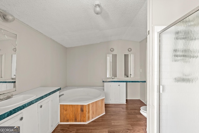 bathroom featuring a textured ceiling, lofted ceiling, wood finished floors, a stall shower, and a bath