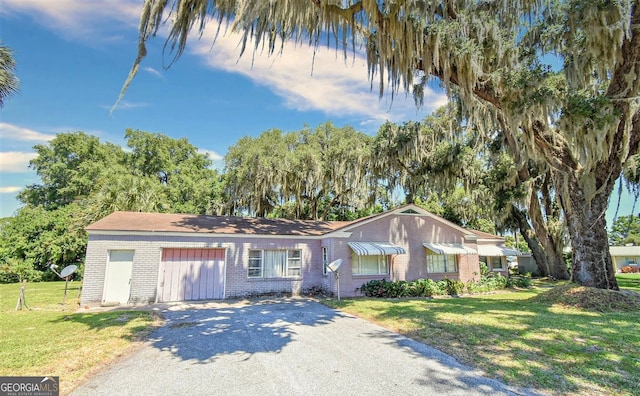 ranch-style home featuring brick siding, driveway, and a front lawn
