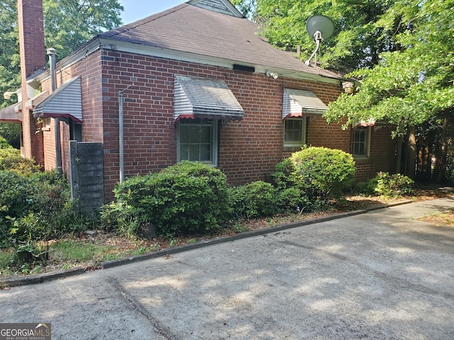 view of home's exterior with brick siding and a chimney