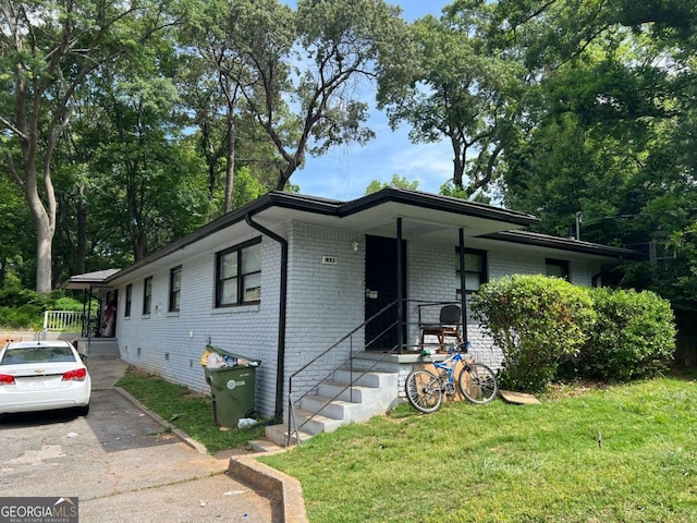 view of front of property featuring a front lawn, brick siding, and driveway