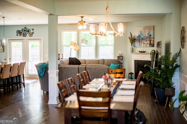 dining room featuring dark wood-style floors, a chandelier, a ceiling fan, and a fireplace